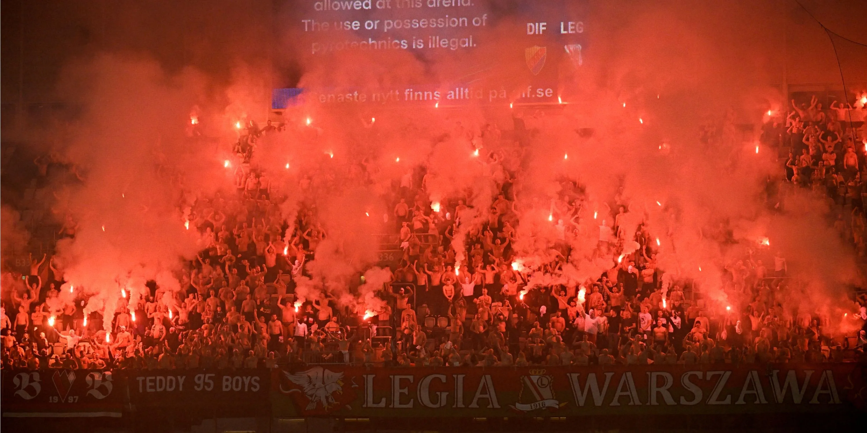 Các cổ động viên Legia Warsaw đốt pháo sáng trên khán đài, tạo ra khung cảnh rực lửa