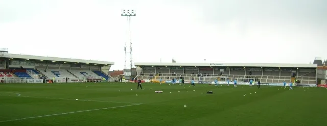 Cầu thủ Hartlepool United khởi động trên sân Victoria Park dưới ánh nắng.
