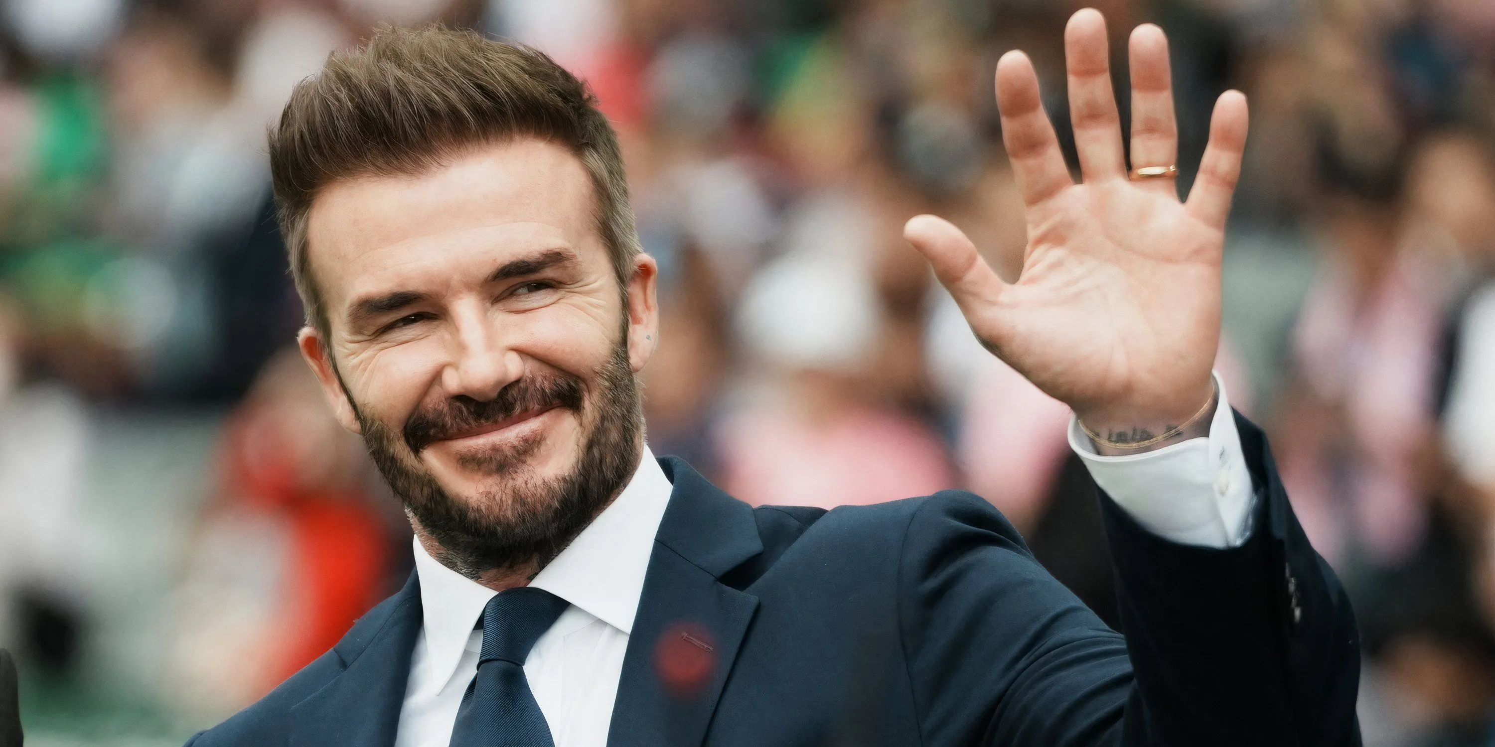 David Beckham, biểu tượng bóng đá, tự hào đứng bên logo Inter Miami, minh chứng cho thành công rực rỡ của ông với tư cách đồng sở hữu CLB MLS này.