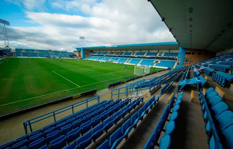 Góc nhìn từ khán đài bên trong sân vận động Priestfield, cho thấy hàng ghế và khung cảnh sân cỏ chờ đợi trận đấu sôi động của Gillingham FC.