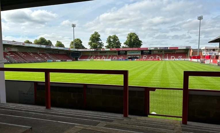 Góc nhìn từ khán đài đứng Speedy Skips Stand tại sân nhà Cheltenham Town