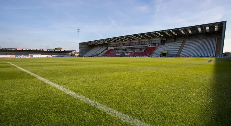 Góc nhìn từ khán đài ra sân cỏ xanh mướt của Mazuma Mobile Stadium, sân nhà của Morecambe FC.