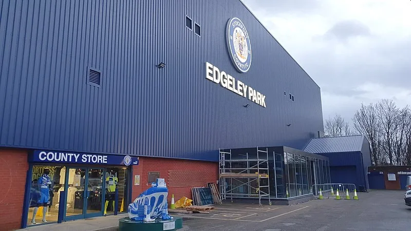 Khán đài Cheadle End và cửa hàng bán đồ lưu niệm bên ngoài sân Edgeley Park.