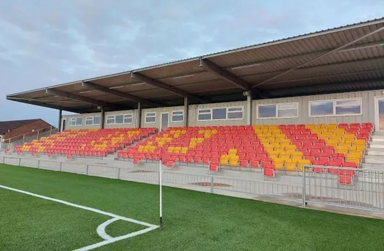 Khán đài có mái che với hàng ghế đỏ của sân Meadow Park Gloucester, nhìn từ góc sân.