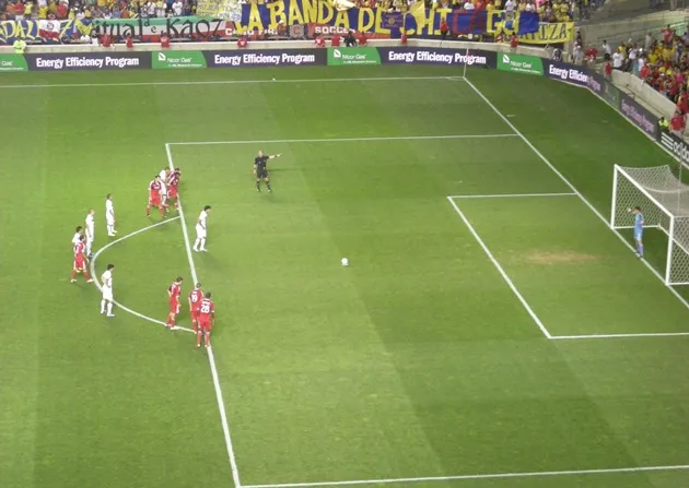 Vạch chấm 11m rõ ràng trên mặt sân, gần khu vực khung thành và vòng cấm.